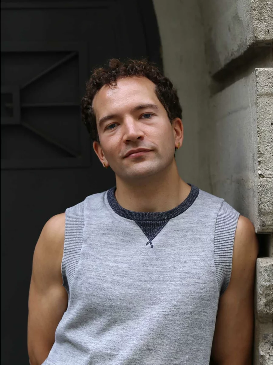 Mathis lehnt lässig am Bunkereingang, vor rauer Betonstruktur und dunkler Tür, Teil des Boros Collection Teams