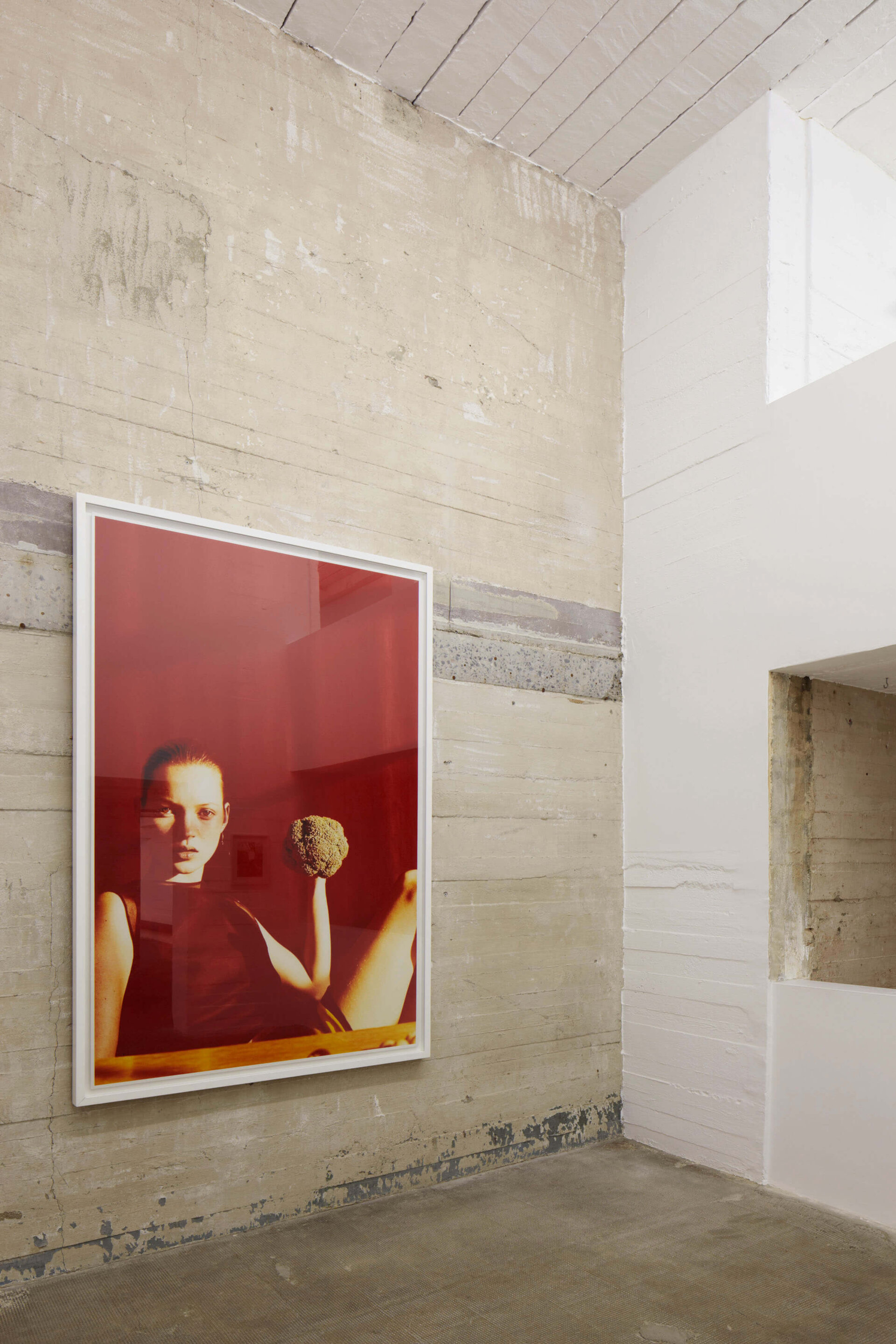 Farbfoto von Wolfgang Tillmans zeigt Kate Moss 1996 in rotem Raum mit Brokkoli in der Hand, ausgestellt an Betonwand im Boros Bunker.