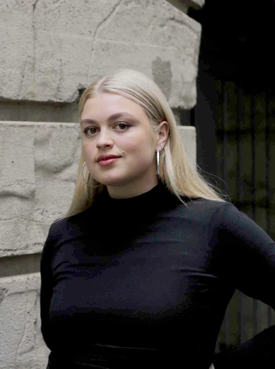 Lena in schwarzem Rollkragenpullover vor dem historischen Mauerwerk des Boros Bunkers