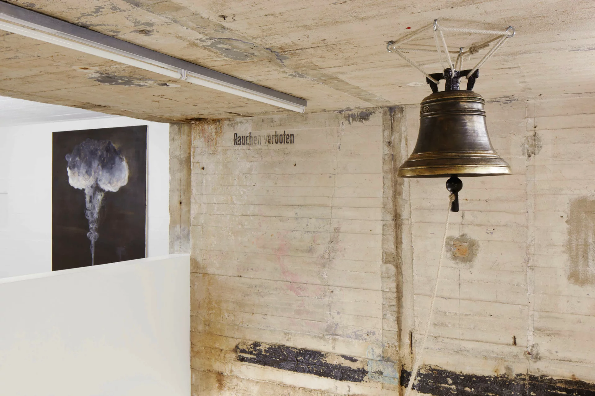 Installation von Thomas Zipp im Boros Bunker: bronzefarbene Glocke mit Seilzug und Gemälde mit Rauchwolke thematisieren Klang und Spiritualität.