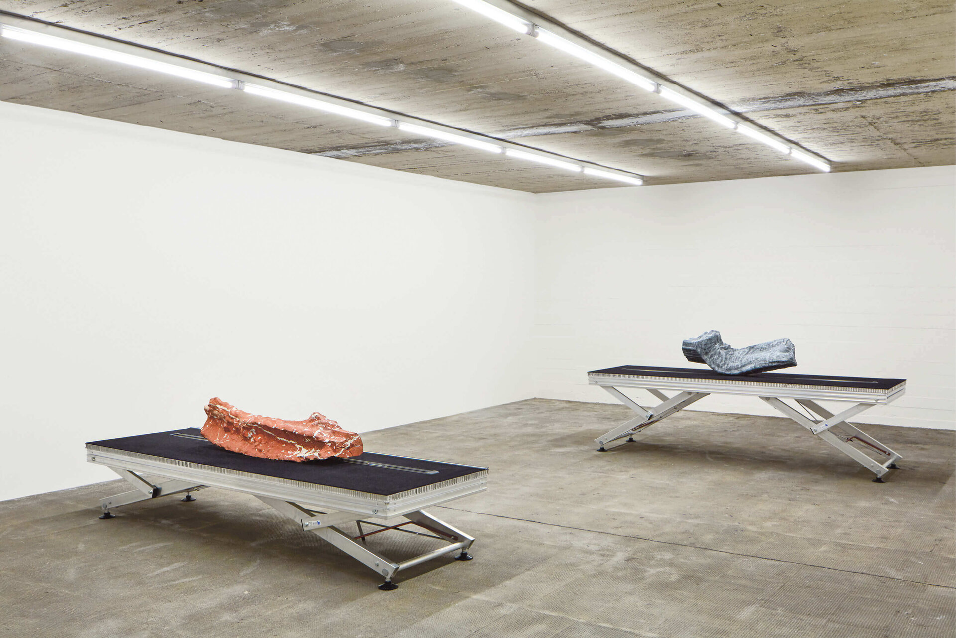 Zwei metallische Skulpturen auf schwarzen Hebebühnen in weißem Ausstellungsraum – Werk von Yngve Holen in der Boros Collection.