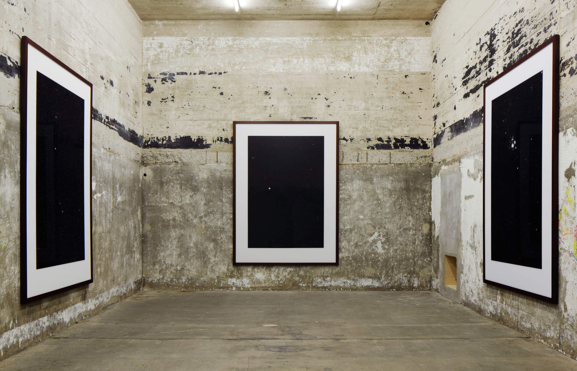 Drei großformatige Sternenfotos von Thomas Ruff an rauen Betonwänden, detailreiche Astronomie vor tiefschwarzem Hintergrund.