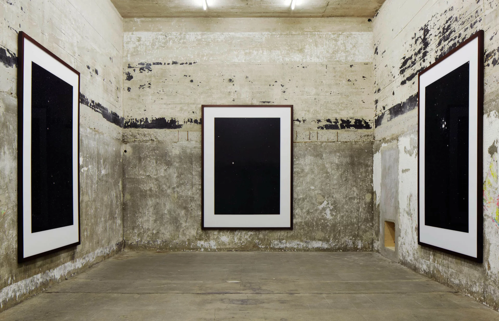 Drei großformatige Sternenfotos von Thomas Ruff an rauen Betonwänden, detailreiche Astronomie vor tiefschwarzem Hintergrund.