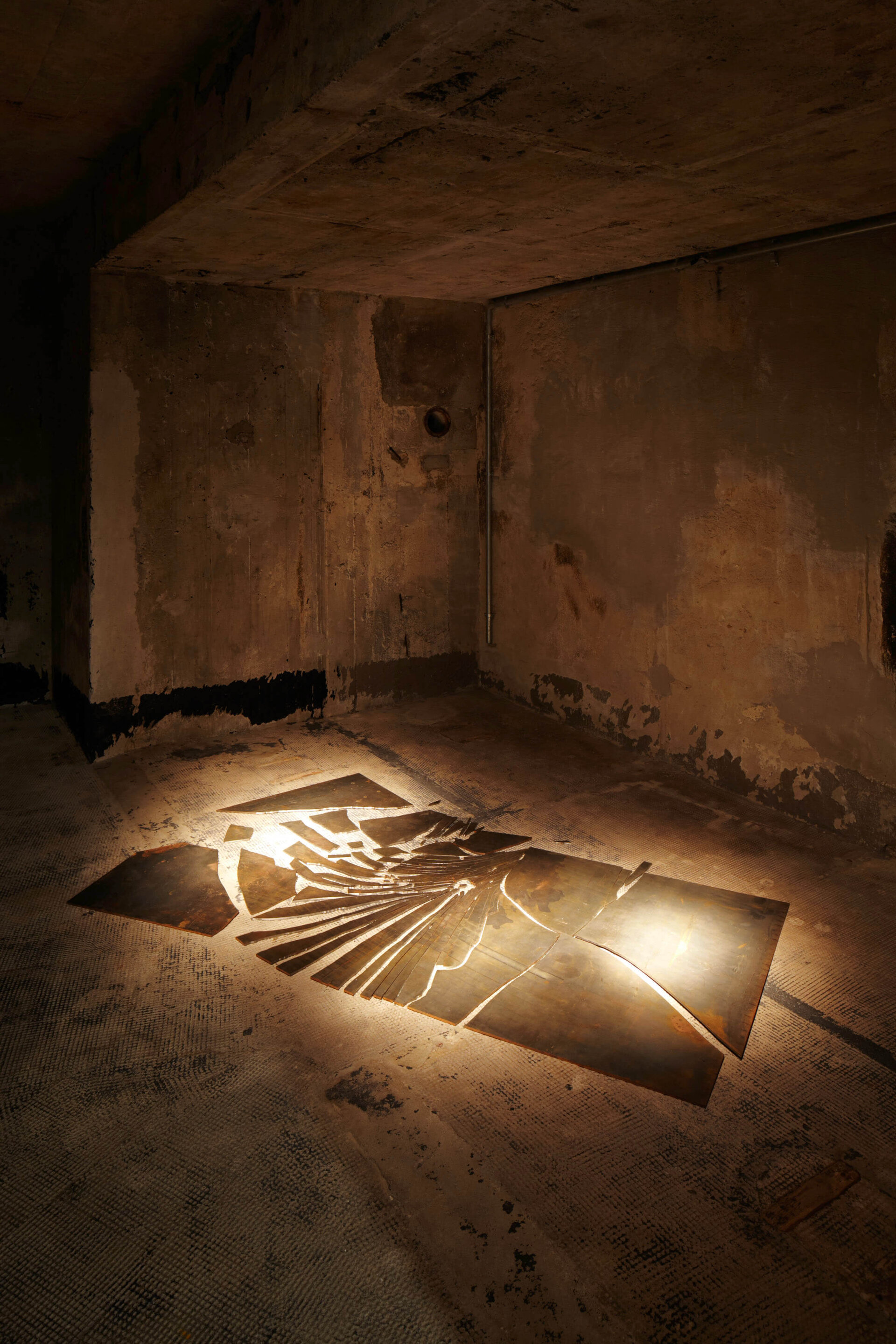 Metallplatten bilden auf dem Boden eine abstrakte Spirale – Alicja Kwades Unter anderer Bedingung (2008) im dunklen Raum der Boros Collection.