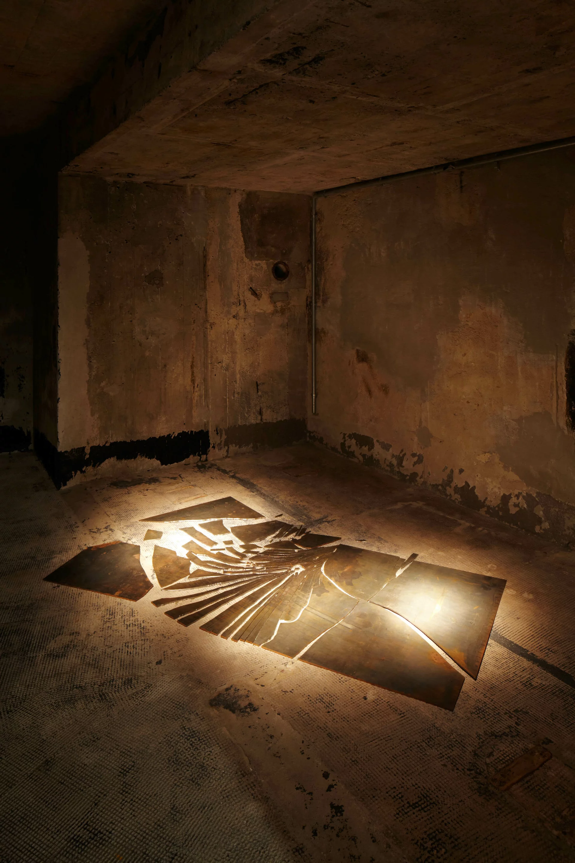 Metallplatten bilden auf dem Boden eine abstrakte Spirale – Alicja Kwades Unter anderer Bedingung (2008) im dunklen Raum der Boros Collection.