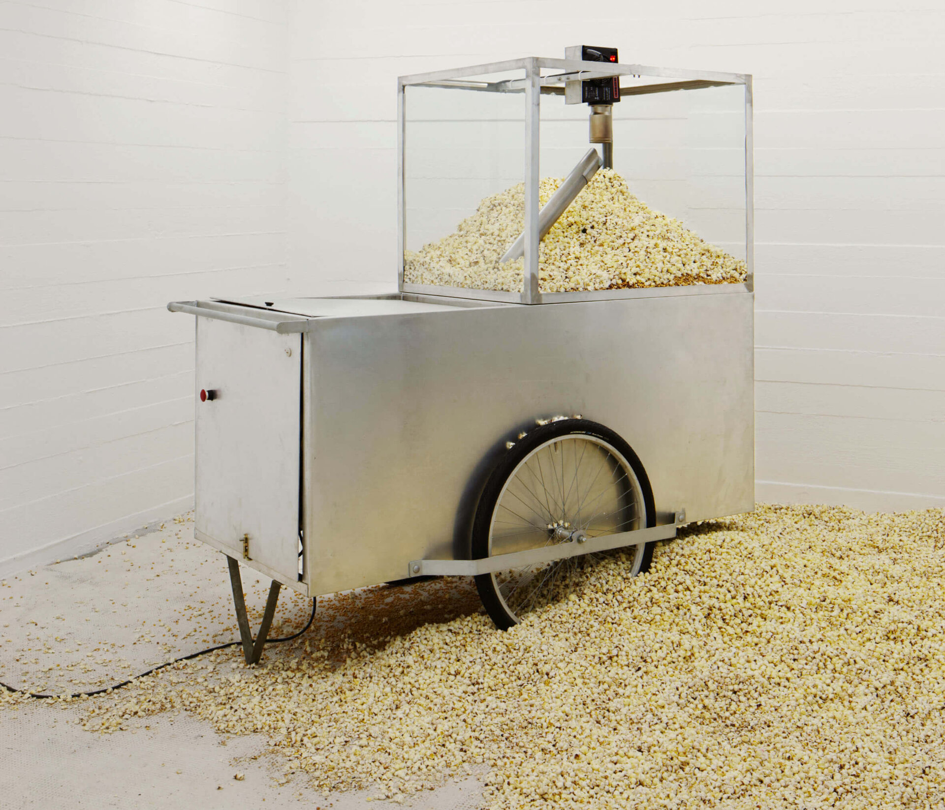 Michael Sailstorfers 1.43–47 (Frankfurt) zeigt eine Popcornmaschine im weißen Raum – das überquellende Popcorn thematisiert Konsum und Überfluss.