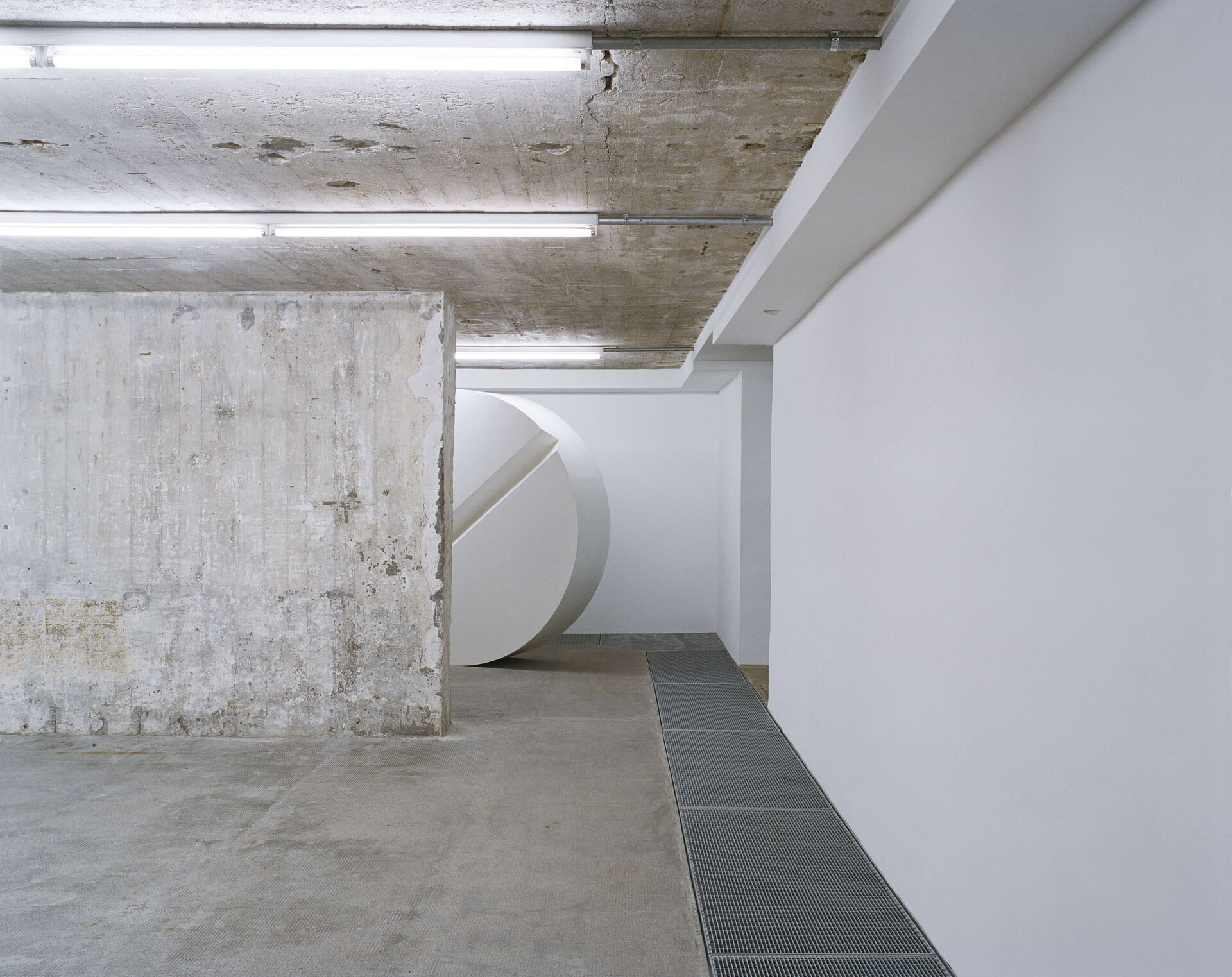 Minimalistische Installation mit weißem Kreiselement vor Betonwand in einem Ausstellungsraum der Boros Collection.