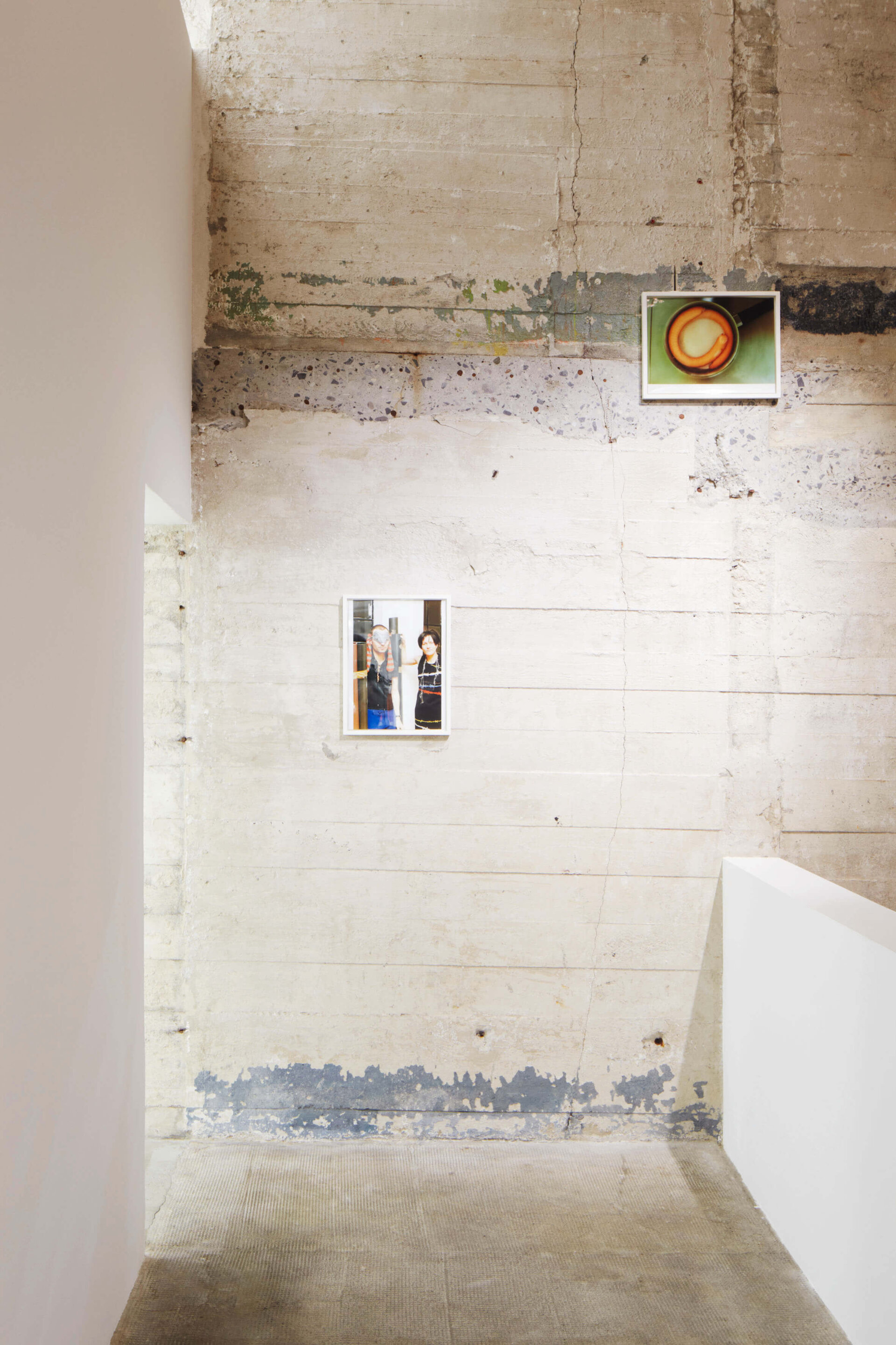 Zwei Fotos von Wolfgang Tillmans im Treppenbereich des Boros Bunkers: oben Würstchen im Topf, unten Porträt zweier Personen im Raum.