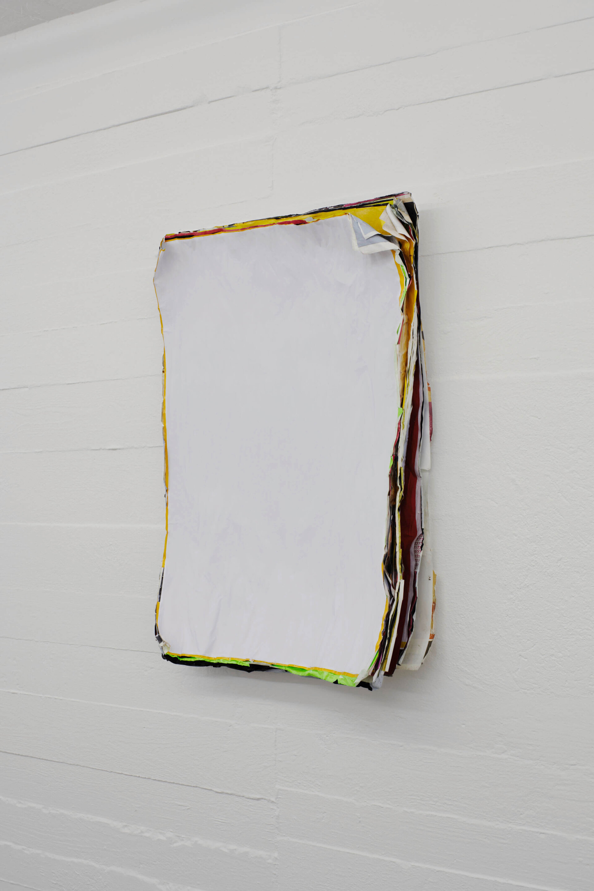 Wandobjekt von Klara Lidén bestehend aus übereinander geschichteten, teils eingerissenen und übermalten Plakaten mit weißer Fläche; die bunten Ränder deuten auf das verborgene Bildmaterial im Inneren.
