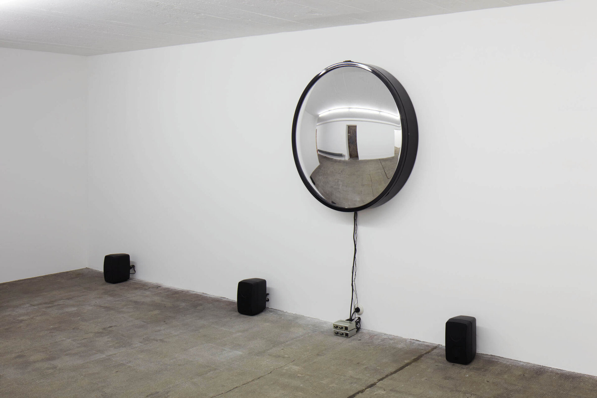Runder Spiegel mit Lautsprechern und Kabeln im Raum – Alicja Kwades Singularität (2009) verbindet visuelle und akustische Wahrnehmung.