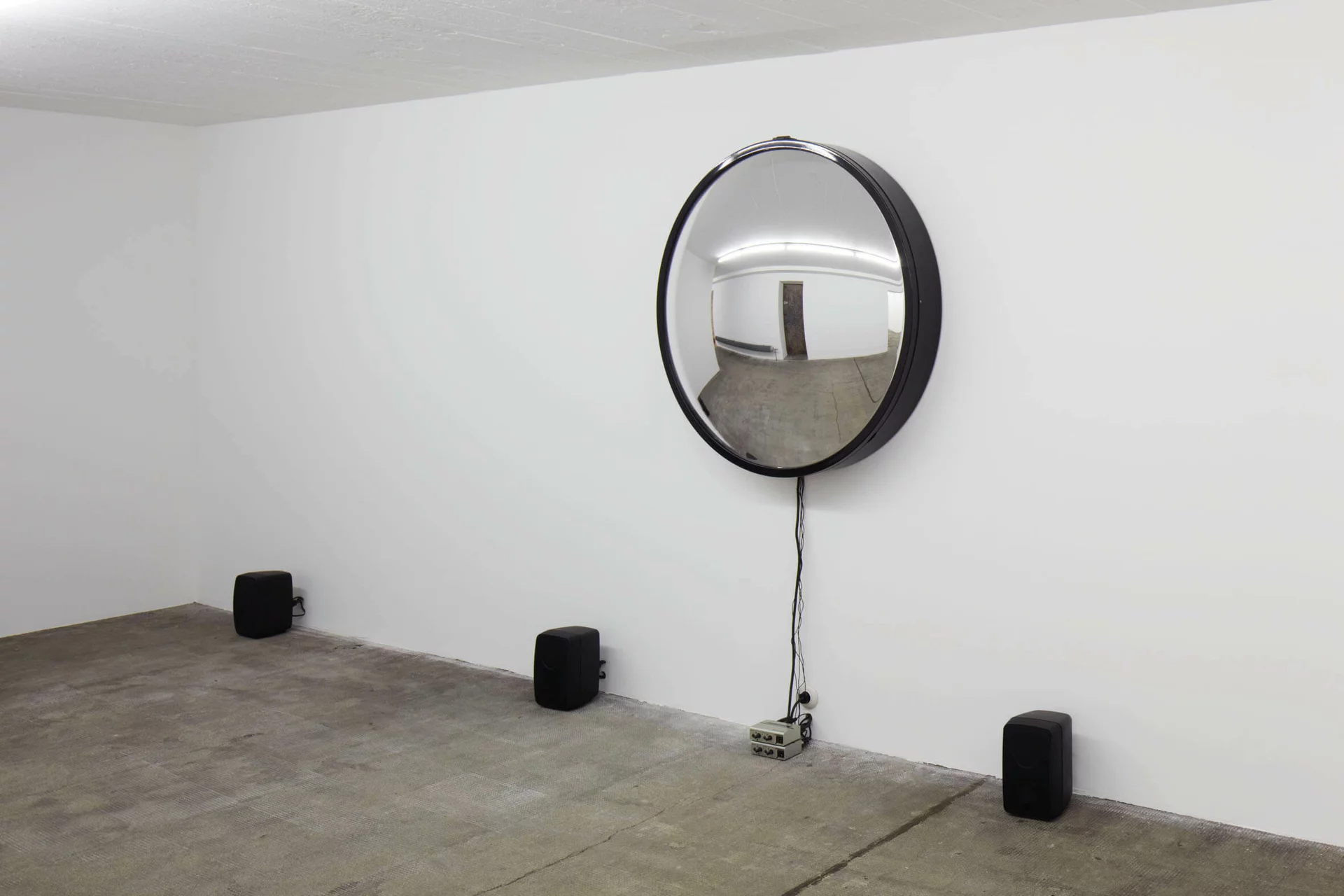 Runder Spiegel mit Lautsprechern und Kabeln im Raum – Alicja Kwades Singularität (2009) verbindet visuelle und akustische Wahrnehmung.