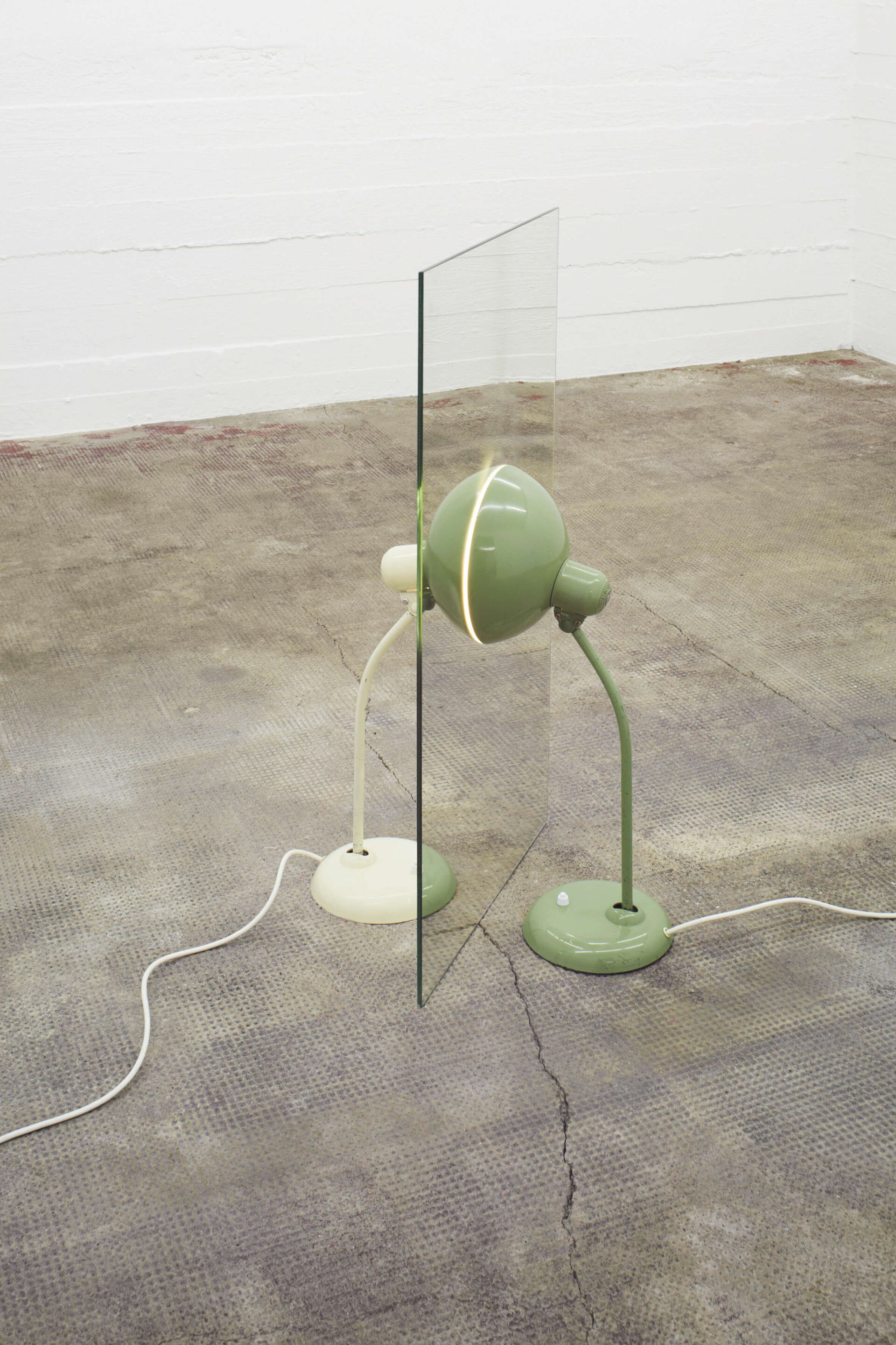 Zwei Tischlampen, grün und weiß, stehen beidseitig an Spiegel – Alicja Kwades Parallelwelt (grün/weiß) (2012) erzeugt symmetrische Lichtillusion.