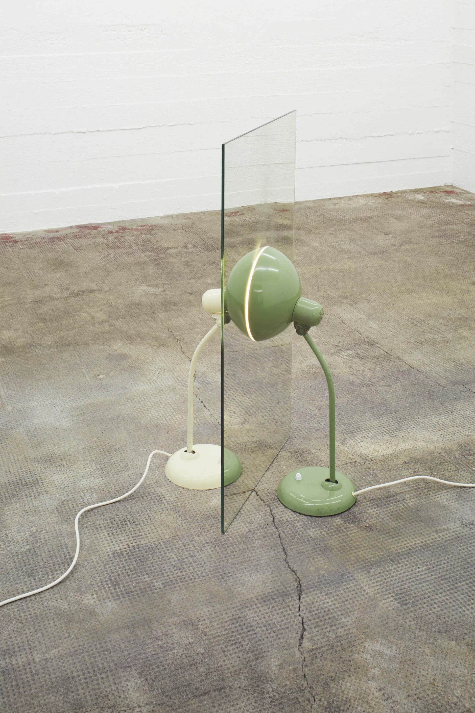 Zwei Tischlampen, grün und weiß, stehen beidseitig an Spiegel – Alicja Kwades Parallelwelt (grün/weiß) (2012) erzeugt symmetrische Lichtillusion.