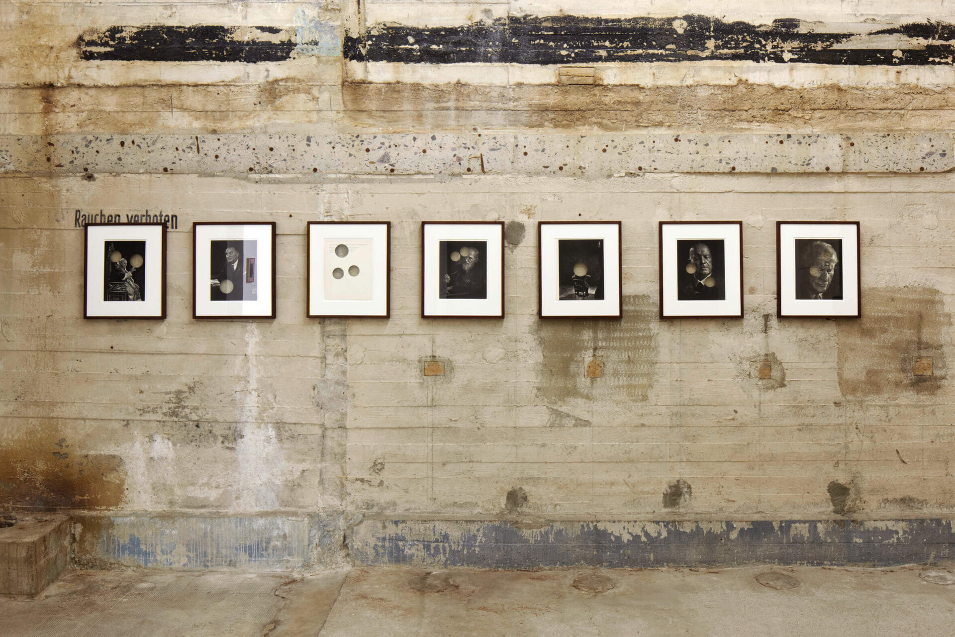 Sieben Schwarzweißporträts von Cerith Wyn Evans hängen im Boros Bunker; Lichtpunkte verfremden die Gesichter auf gealterter Betonwand.