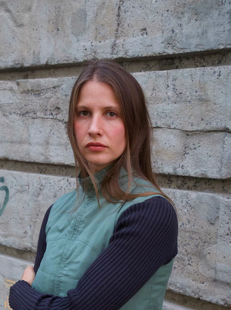 Carlotta vom Team der Boros Collection steht mit verschränkten Armen vor der rauen Betonfassade des Bunkers.