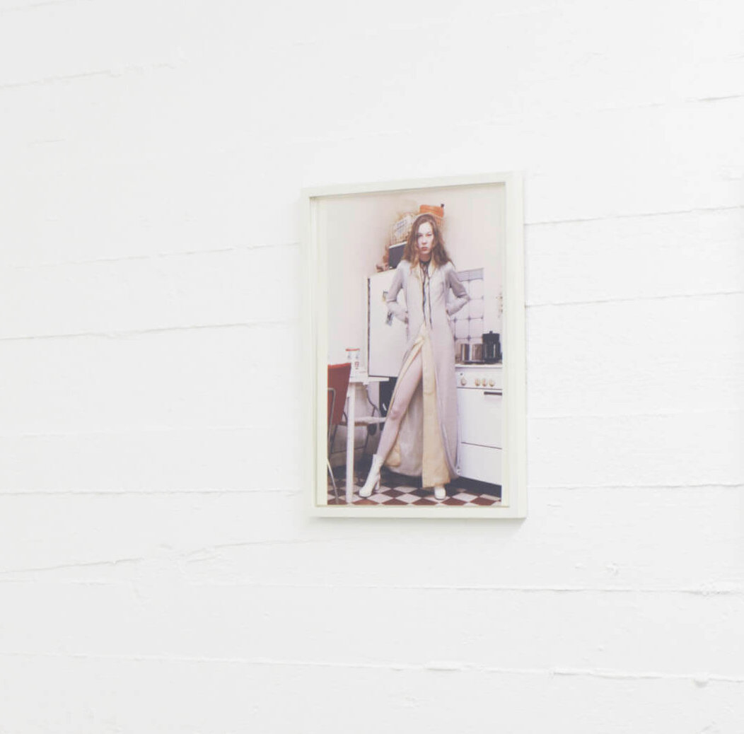 Farbfotografie von Wolfgang Tillmans mit dem Titel Julia aus dem Jahr 1991. Das Bild zeigt eine junge Frau in einem lässigen Moment vor einer Küchenszene. Es hängt an einer weißen Wand im Ausstellungsraum des Boros Bunkers.