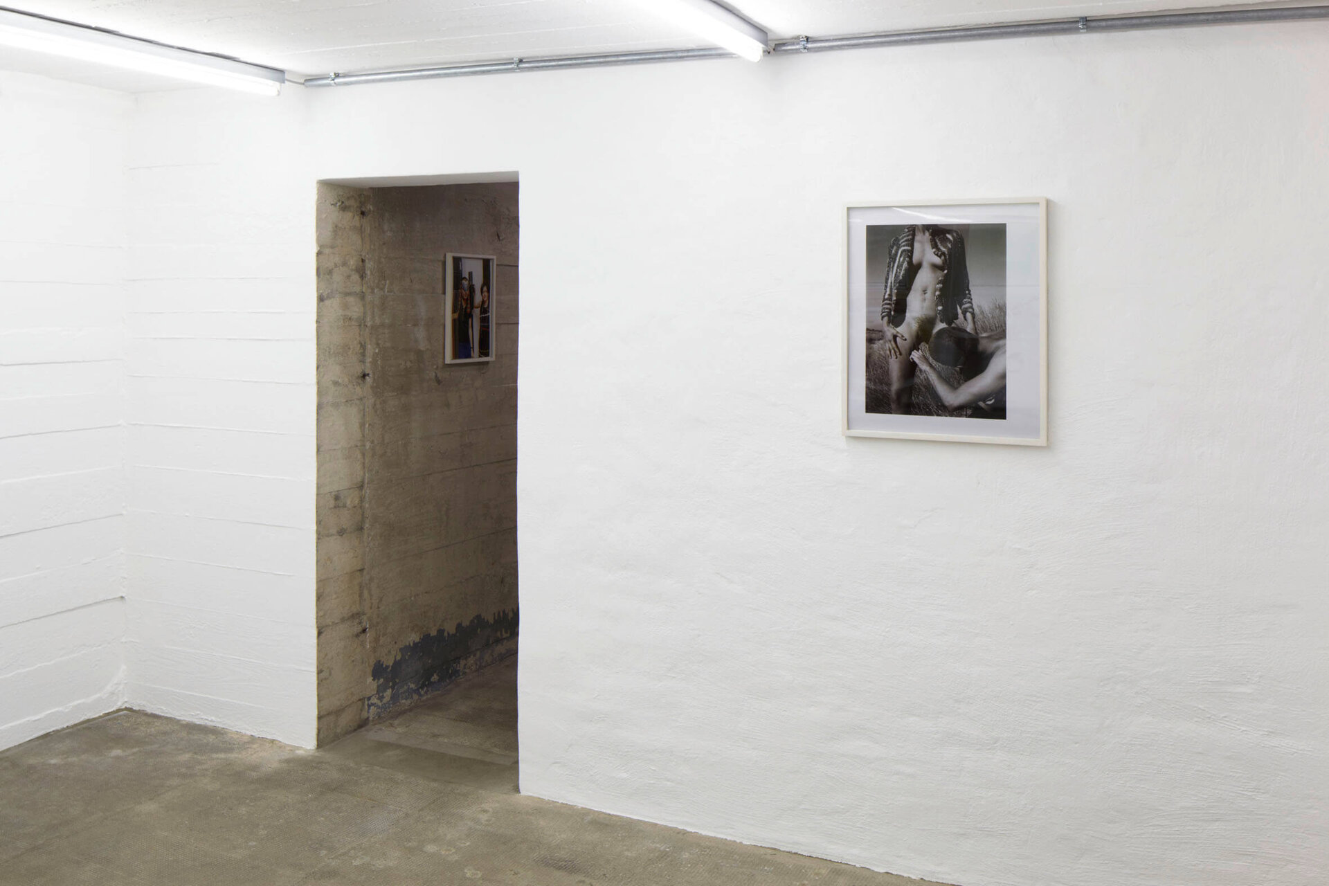 Wolfgang Tillmans’ Foto von 1991 zeigt zwei Personen in intimer Pose auf einem Feld – ausgestellt an weißer Wand im Boros Bunker Berlin.