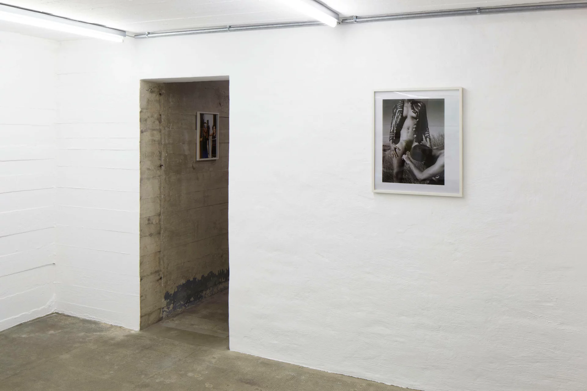 Wolfgang Tillmans’ Foto von 1991 zeigt zwei Personen in intimer Pose auf einem Feld – ausgestellt an weißer Wand im Boros Bunker Berlin.