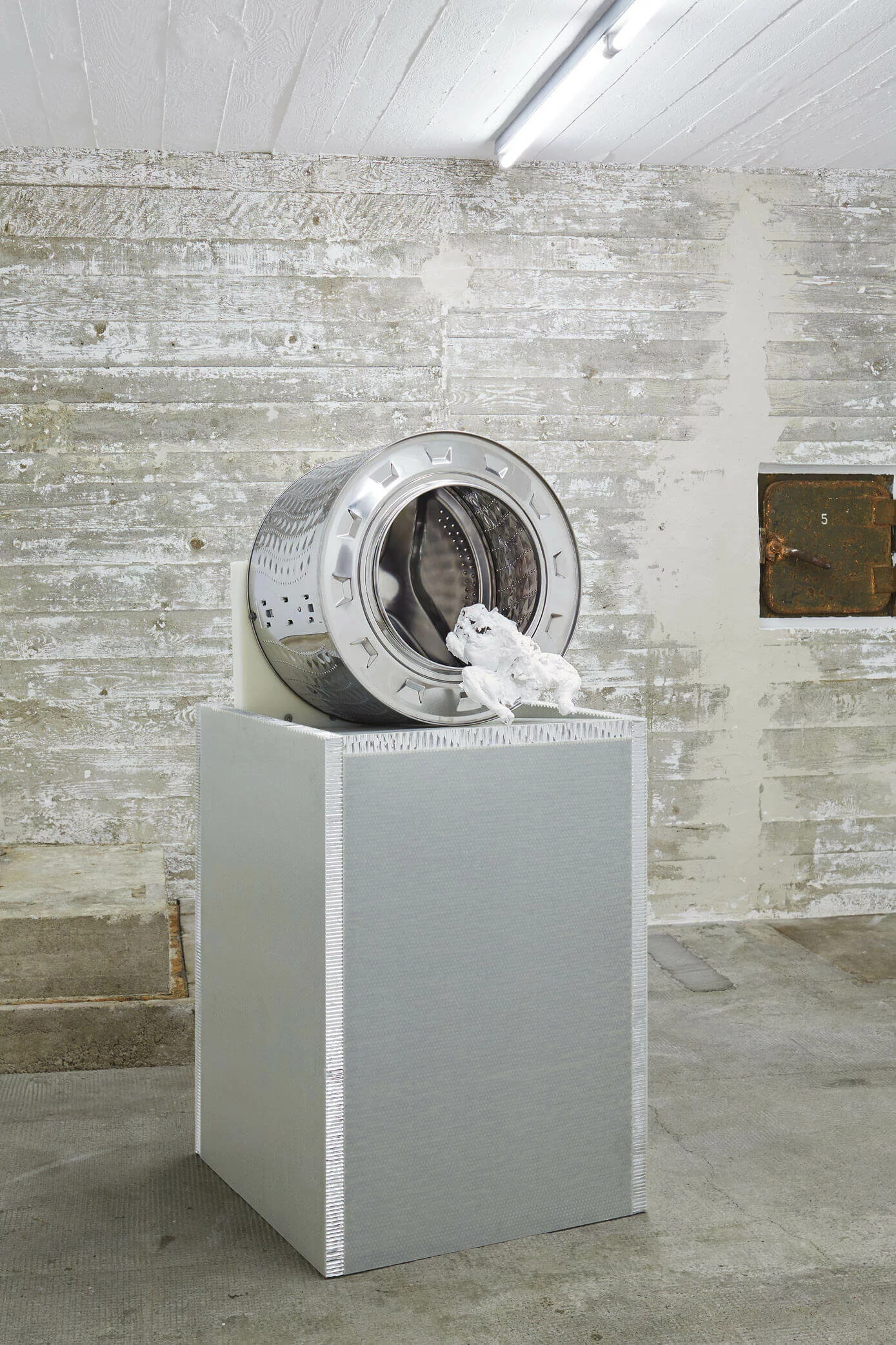 Skulptur mit Waschmaschinentrommel und weißem 3D-Objekt auf silbernem Sockel – Werk von Yngve Holen in der Boros Collection.