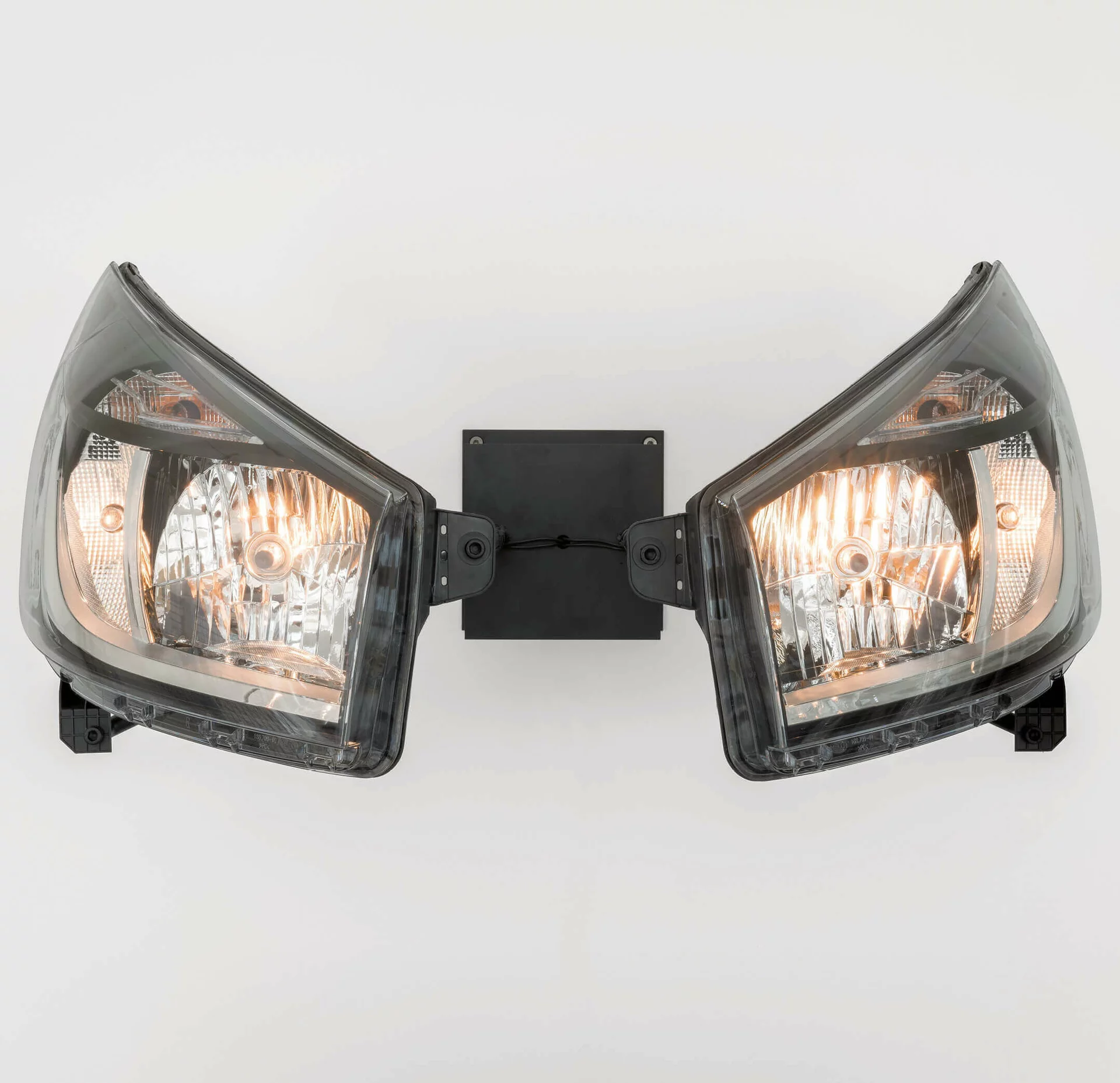 Zwei leuchtende Autoscheinwerfer montiert als Skulptur an einer Wand – Werk von Yngve Holen in der Boros Collection.