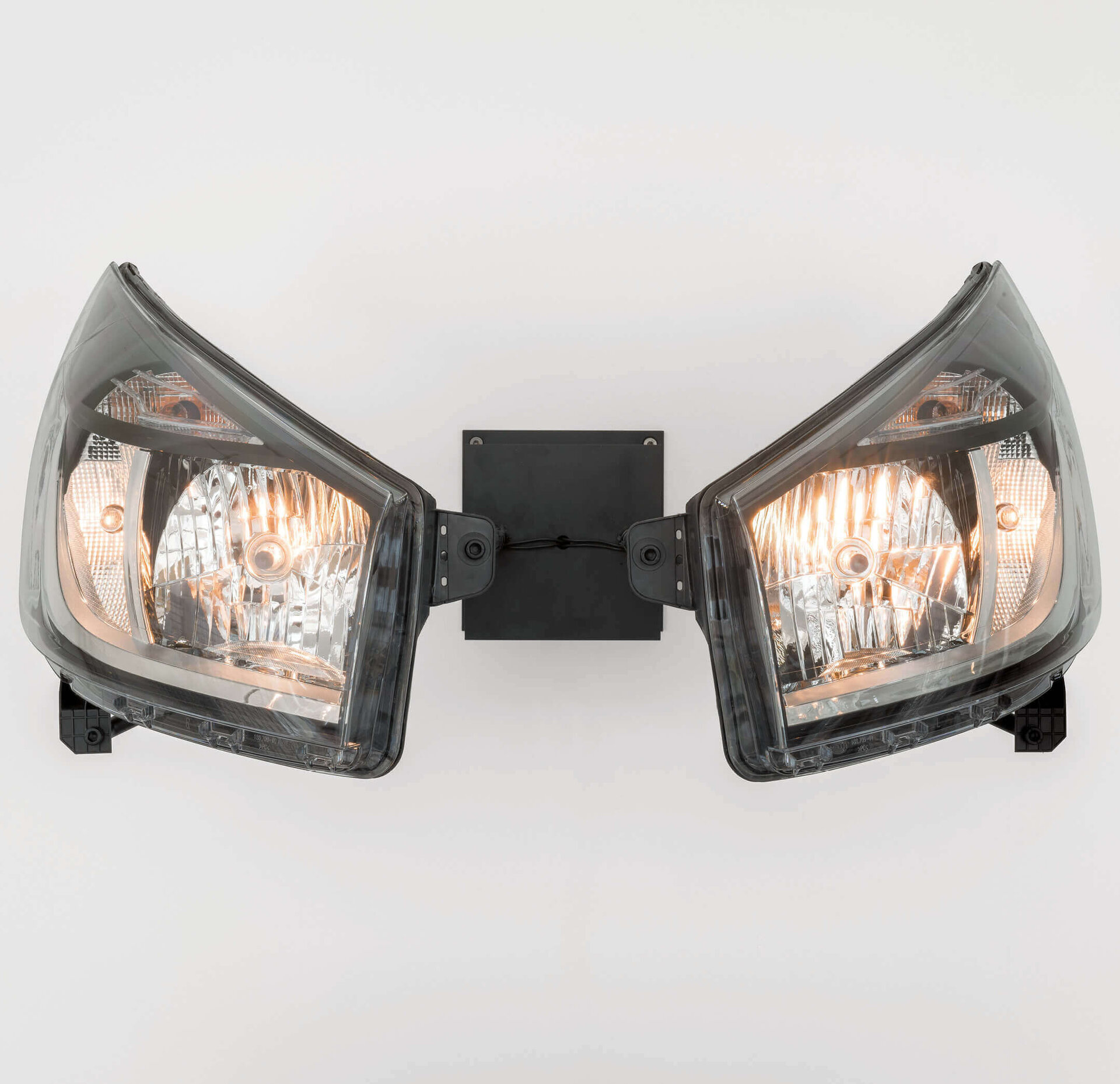 Zwei leuchtende Autoscheinwerfer montiert als Skulptur an einer Wand – Werk von Yngve Holen in der Boros Collection.