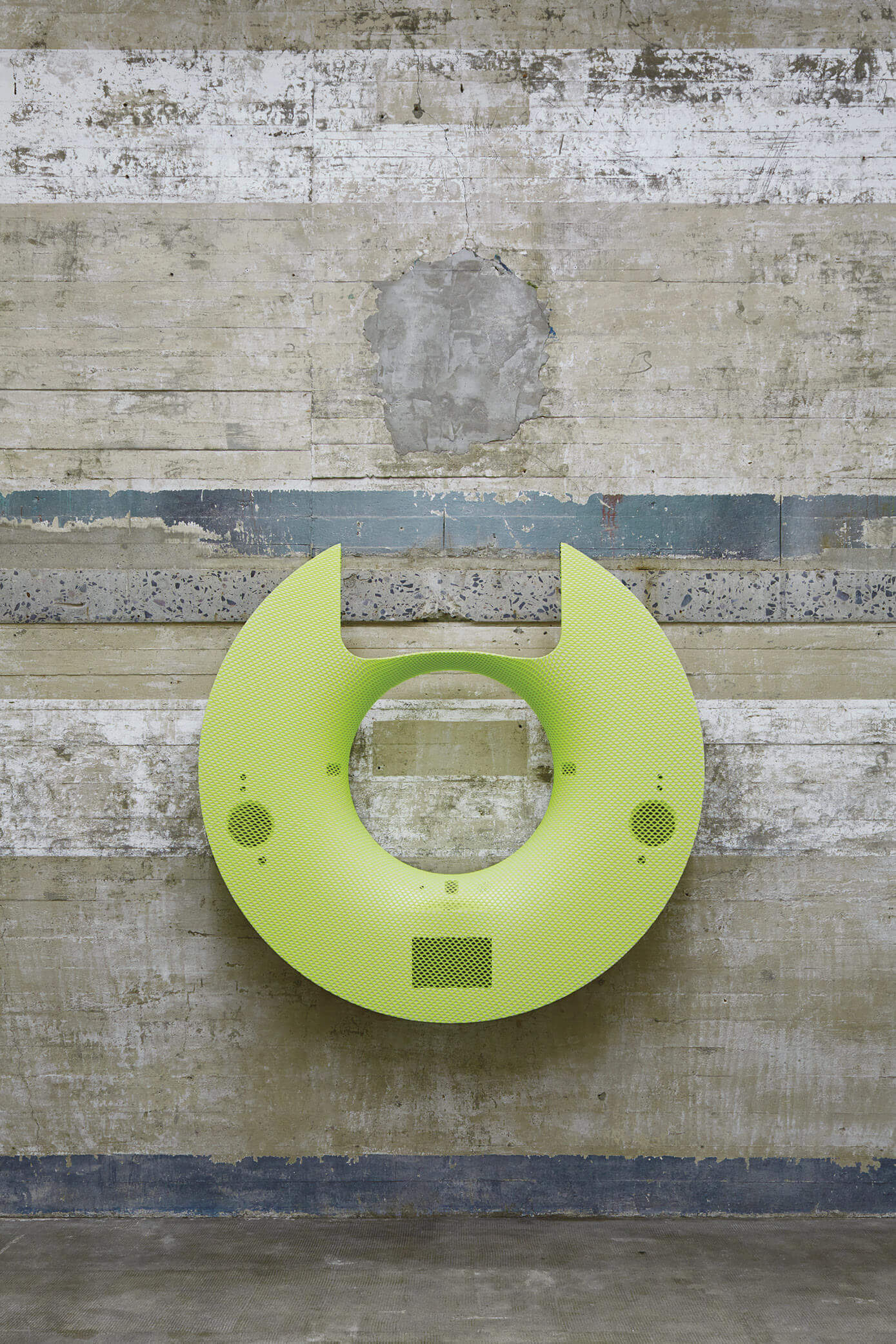 Gelbe, ringförmige Skulptur mit technischen Details an Betonwand – Werk Vuja De von Yngve Holen in der Boros Collection.